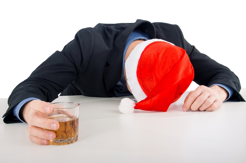 man met kerstmuts en glas alcohol slaapt met hoofd op tafel