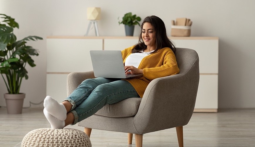 vrouw werkt vanuit gemakkelijke stoel op de laptop