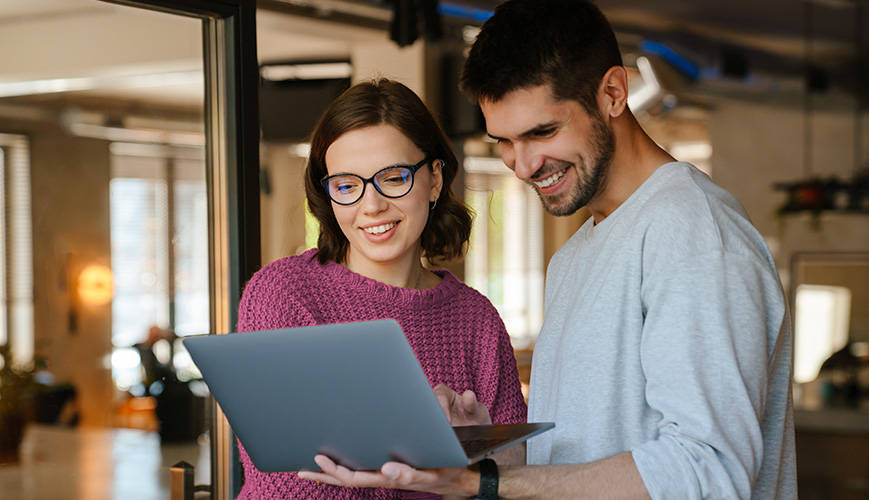 Twee collega's kijken samen naar het beeldscherm van een laptop